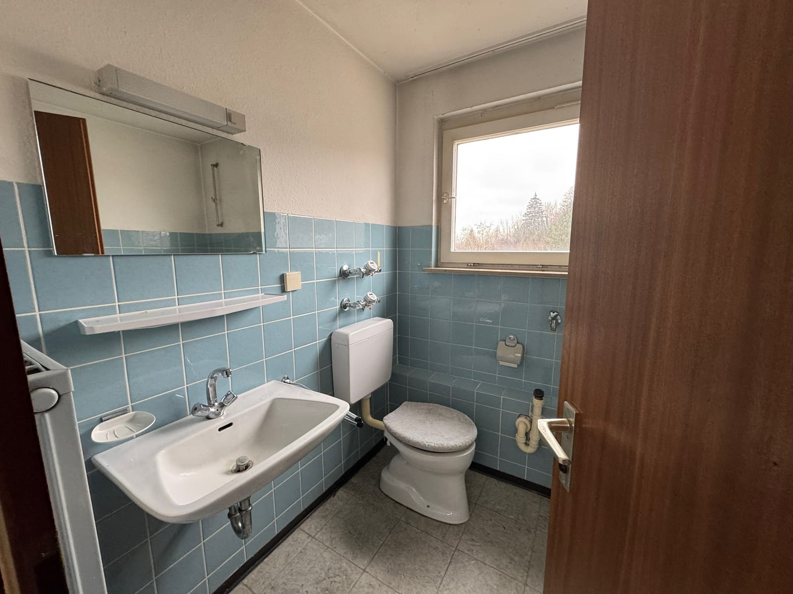 Badezimmer vor der Sanierung mit hellblauen Fliesen aus den 1970er-Jahren