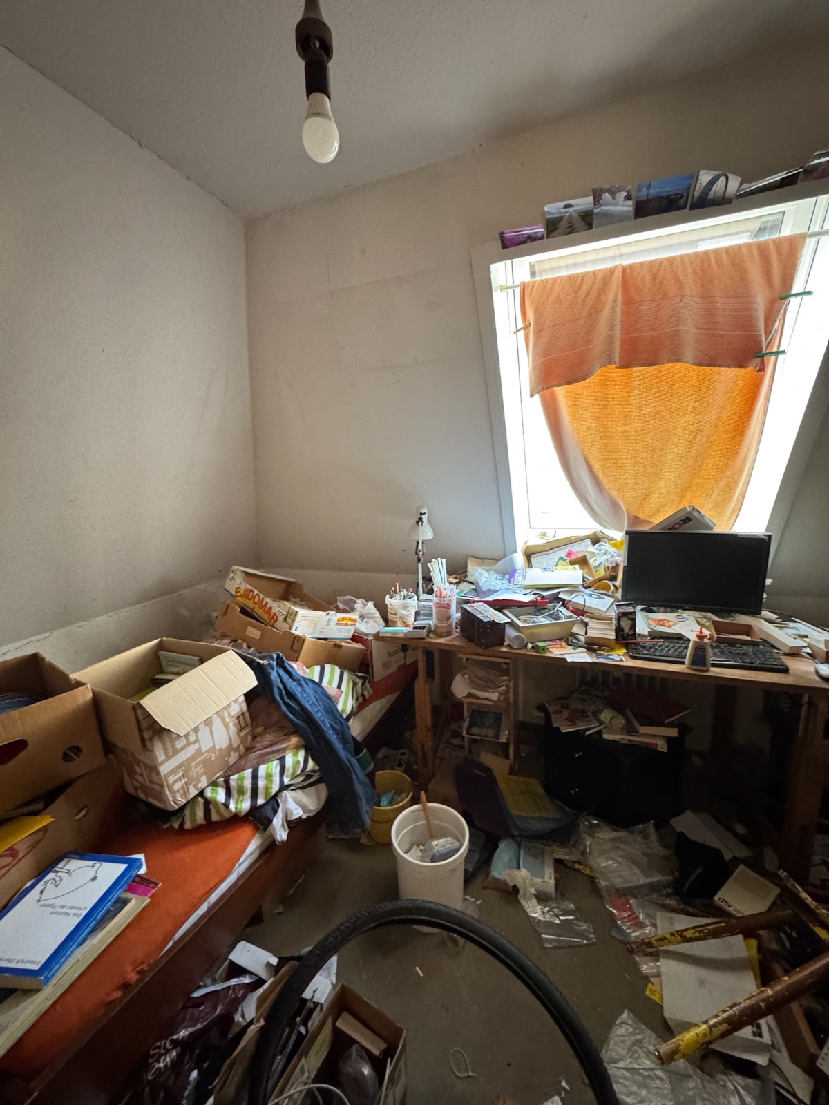 Schlafzimmer vor der Renovierung: vollgestelltes Zimmer mit Kartons, altem Mobiliar und offenem Estrich